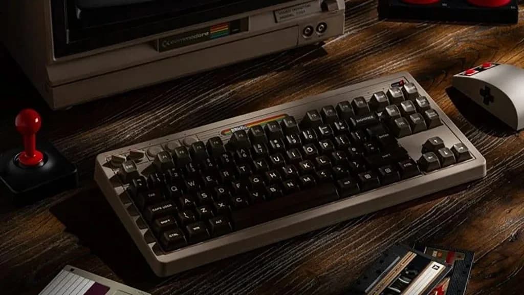 8BitDo Retro Mechanical Keyboard C64 Edition on a wooden desk with its joystick and Super Buttons