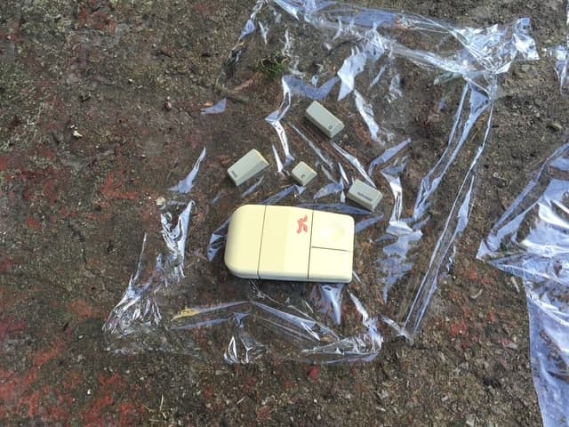 An old mouse and keycaps covered in plastic wrap while RetroBrighting outdoors