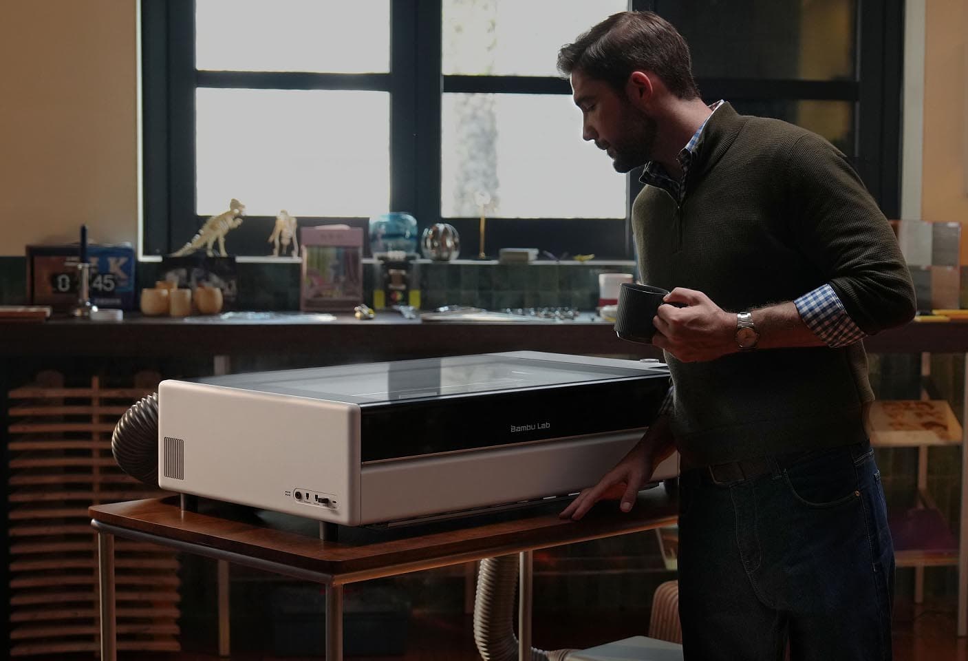 A person operating the enclosed Bambu Lab R1 laser cutter at home