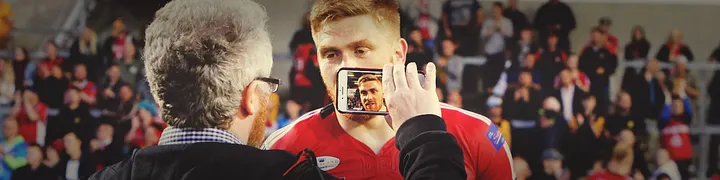 Paul McNally filming a pitchside interview with a Salford rugby league player