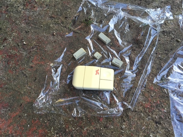 An old mouse and keycaps covered in plastic wrap while RetroBrighting outdoors