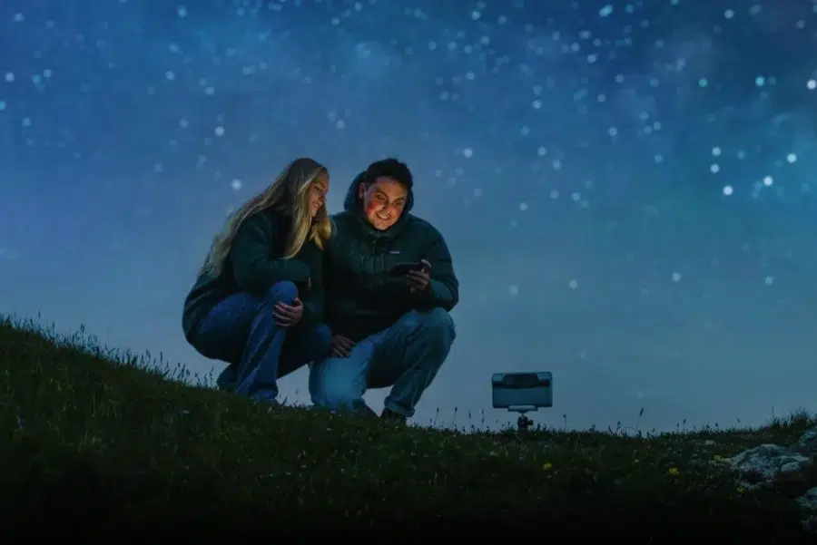 Two people using a Dwarf 3 smart telescope beneath a starry sky
